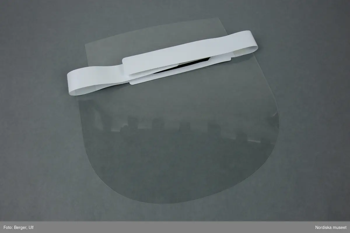 a-b) Skyddsvisir tillverkat av genomskinlig OH-film, vitt plastband samt pannskydd i grått skumgummi.
/Anna Fredholm 2022-10-13