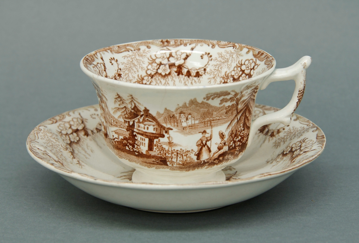 Kopp og skål med påtrykket dekor i brun tone. Alpeinspirert motiv. Del av te- og kaffeservise i 10 deler: Kaffekanne, tekanne og åtte kopper med skåler.