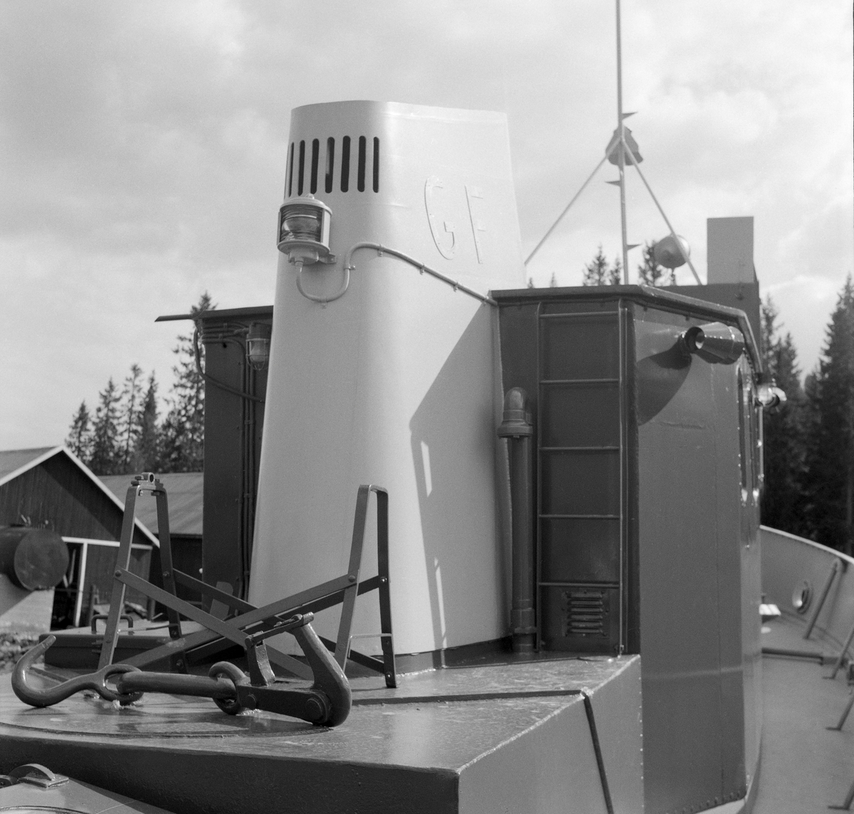 Slepebåten «Trysilknut», fotografert ved slippen på Sørlistøa ved Osensjøen i Åmot kommune i Hedmark i 1964. Fotografiet er tatt fra akterdekket, mot skorsteinen og bakveggen på styrhuset. I forgrunnen ligger slepekroken. I 1964 var dette fartøyet 50 år gammelt. Skroget var slik det alltid hadde vært - 55 fot langt og 12 fot bredt, klinket sammen av det som i 1914 var «bedste sort skibsbygningsstaal», levert av Glommens mek. Verksted i Fredrikstad. Men Trysilknut var i utgangspunktet et dampdrevet fartøy. Dampmaskinen viste seg imidlertid i veikeste laget for de store tømmerbommene som skulle bukseres over den bortimot tre mil lange og 47 kvadratkilometer store Osensjøen. Etter 2. verdenskrig ble mange av slepebåtene som fellesfløtingsforeningene disponerte ombygd til dieseldrift. Lederne i Glomma fellesfløtingsforening planla modernisering av Trysilknut ut fra en overbevisning om at man på litt lengre sikt skulle oppnå større trekkraft og samtidig redusere driftskostnadene. Dieselmotorene krevde nemlig langt mindre betjening enn dampmaskinene, og følgelig ville en dieseldrevet slepebåt kunne opereres med mindre mannskap enn et dampfartøy. I Trysilknuts tilfelle så man for seg at to fyrbøtere og en maskinist kunne utgå fra besetningen. Her lå det et betydelig innsparingspotensial i en periode med stigende lønnskostnader. I 1956 sendte direktøren i Glomma fellesfløtingsforening prisforespørsler til firmaer som man antok kunne påta seg ombyggingsarbeidet. Oppdraget gikk også denne gangen til Glommens mek. verksted. Demonteringa av dampmaskinen innebar også at det ble en del ledig plass om bord. Ominnredningsarbeidet ble overlatt til Ivar Hagens båtbyggeri på Hjelset utenfor Molde. Resultatet ble at Trysilknut - etter ombyggingsarbeidet vinteren 1957-58 framsto med et noe endret eksteriør og et fullstendig modernisert interiør.