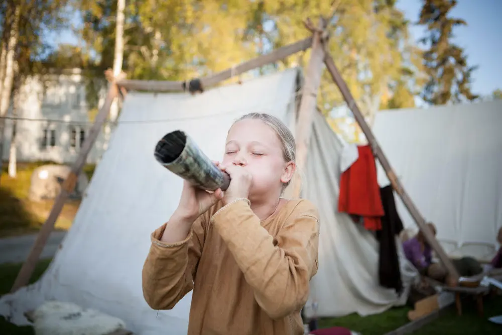 Bildet viser et barn som blåser i et horn.