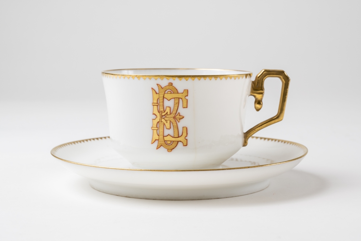 Kaffekopp, 6 st. av vitt porslin med förgylld dekor i form av tandad bård och monogram: "EB" (= Edward Björkman). Profilerat förgyllt handtag. En kopp är spräckt. Samhör med: JM.18150:4 (fat).