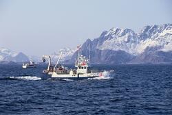 To fiskebåter på havet, Lofoten, med Lofotveggen i bakgrunne
