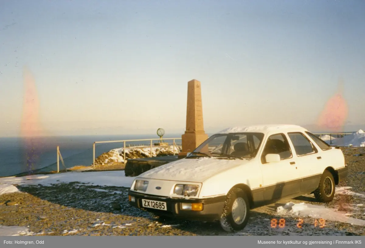 Nordkapp. Prosjekt "Nordkapp 1990". Utbygging av Nordkapphallen. En bil ved Oscarstøtten på platået. I bakgrunnen ser man Globusen. 19.02.1988.