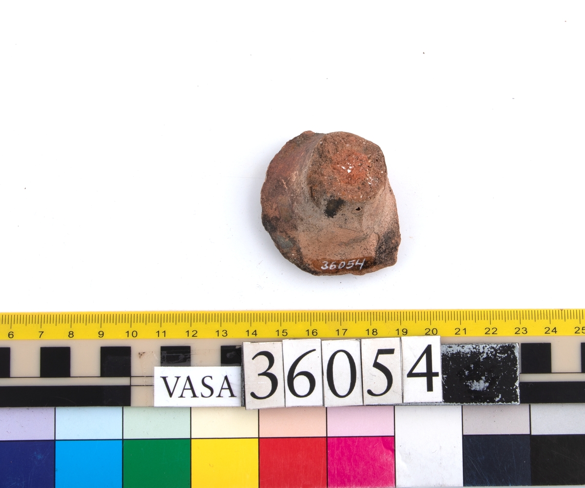 En keramikskärva, bit av ben (avslaget) H 30 mm. Fragment. Insida av botten blyglaserad grönbrun.