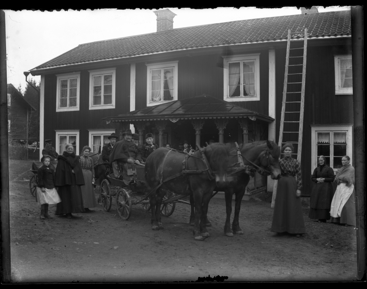 Grupporträtt, med hästar och vagn framför gårdens veranda.