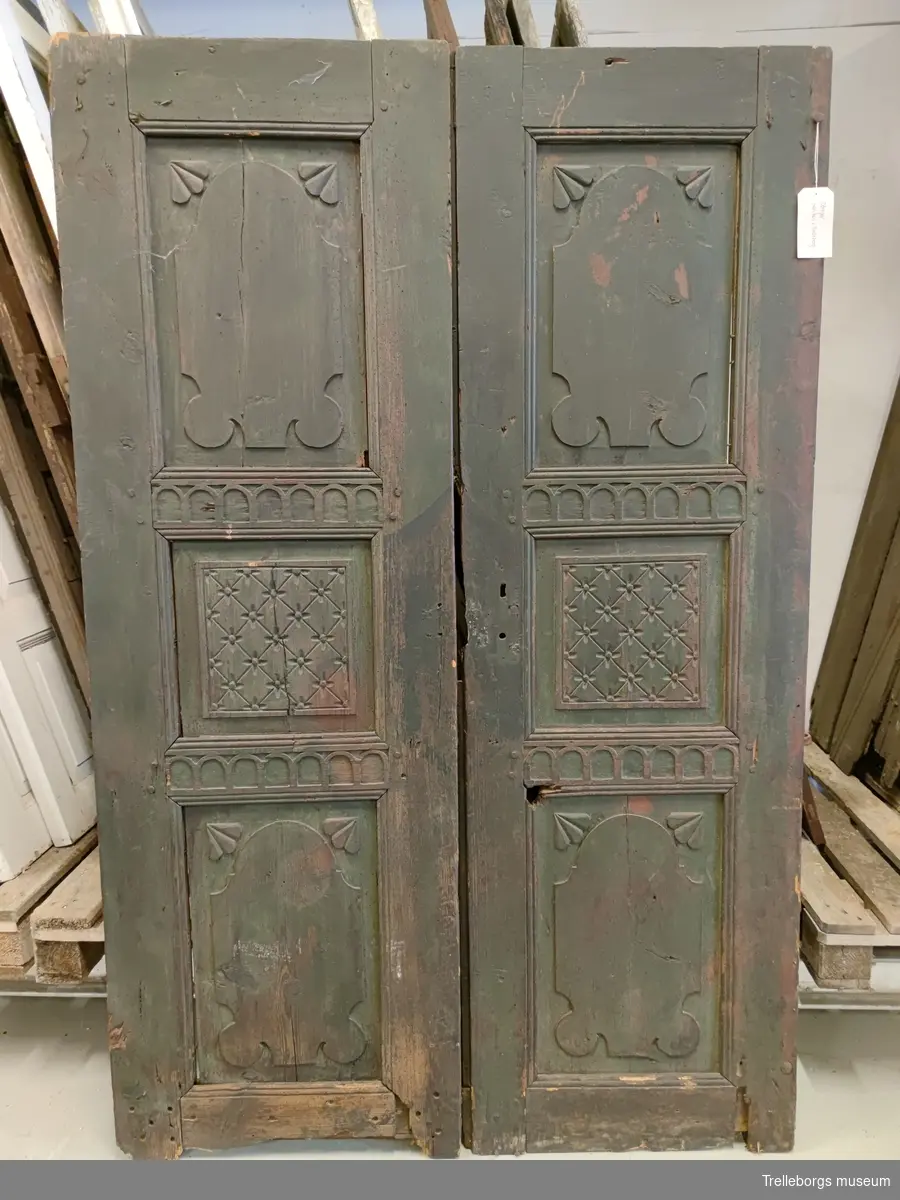 Pardörr utan karm. Ett par, två stycken, dörrar.
Tredelad spegel med karvsnitt, på båda dörrarna.
Mörkt grön, målad. Ser ut att möjligen ha varit rödmålad tidigare.