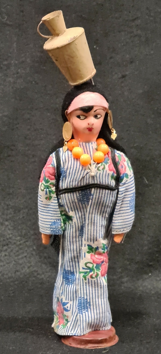 Docka som tillhör Vera Hanssons docksamling.

Köpt 1965. Ramses, Egypten. Afrika. Brunrandig toga och röd mössa. Käppar i händerna och cigarett i munnen.