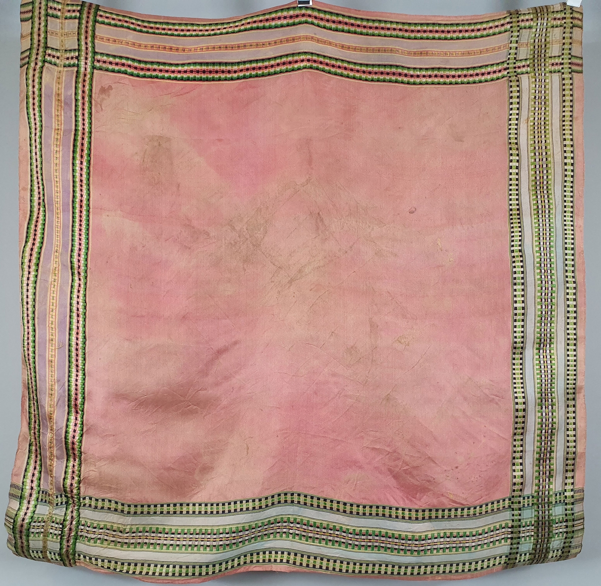 Mørk rosa sjal av silke med striper i grønt, svart og gult langs kantene.