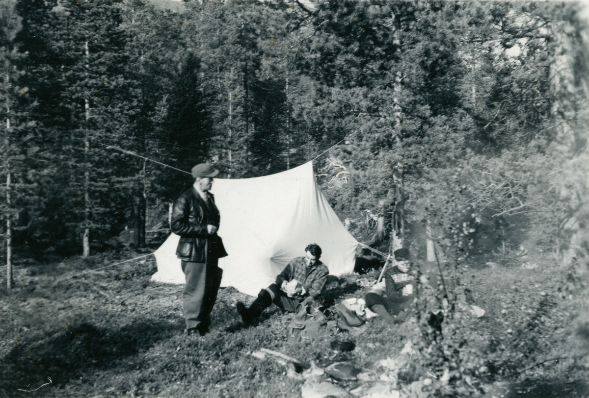 Tre menn foran et telt i Ansamokka, Reisadalen.