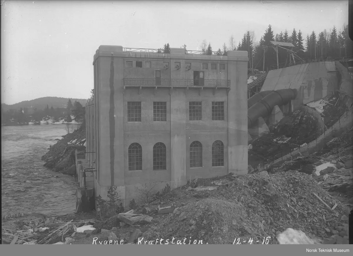 Eksteriørbilde av Rygene kraftstasjon med uttak og rørledning : kraftstasjonen eies av A/S Rygene Tremassefabrikker og ble bygget i 1913-14, senere ble det bygget ytterligere to kraftstasjoner tilhørende samme anlegg