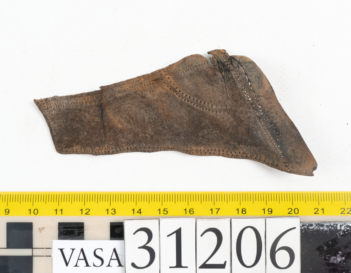 Delar av överdelen till en sko. Skon är ej samtida med förlisningen av Vasa.
En del av ovanläder i form av ett större läderstycke försett  med snörhål. Sex mindre delar från skons överdel. Delarna har hål efter stygn och två av bitarna har snörhål. Lädret är något rostfärgat.