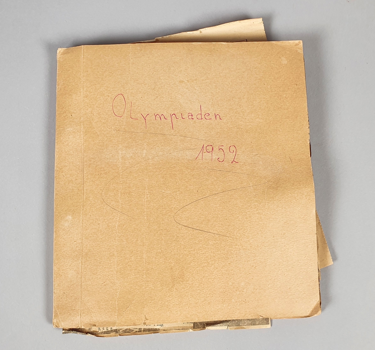 Mappe med innsatte ark, med pålimte avisutklipp om vinter-OL i Oslo 1952, og med håndskrevne overskrifter, notater og kommentarer.