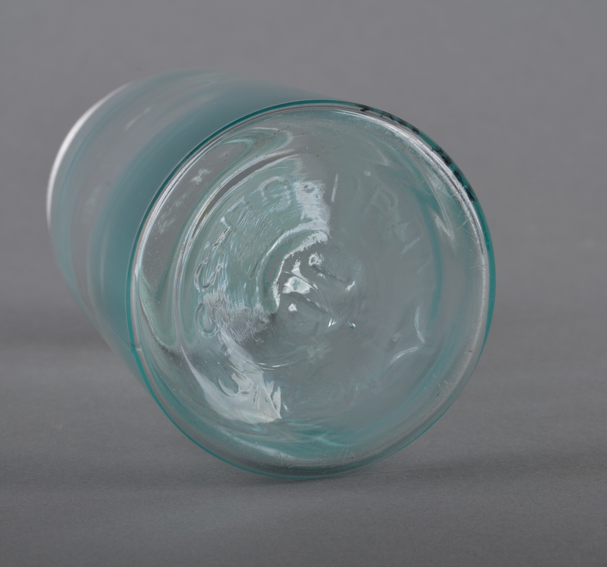 Sylindrisk glassbeholder med glasslokk som har gjenget metallring. Glasset er gjennomsiktig.