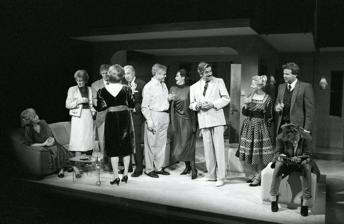 Scene fra Nationaltheaterets oppsetning av Alan Ayckbourns "Monki Bisniss". Elleve kvinner og menn kledd for fest står i en gruppe, der de prater og drikker. Scene fra Nationaltheaterets oppsetning av Alan Ayckbourns "Monki Bisniss". Forestillingen hadde premiere 8. september 1989. Toralv Maurstad hadde regi og medvirkende var blant annet Tor Stokke som Jack, Kari Simonsen som Poppy og Leif Juster som Ken Ayres. 