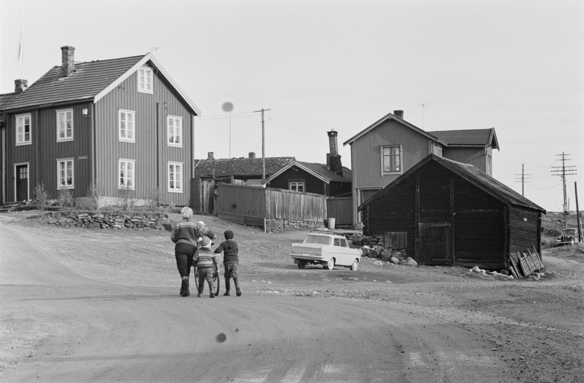 En kvinne og to barn går blant bebyggelsen på Røros.