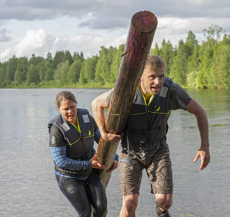 Bilder viser to mann og kvinne  fra Glommen/Mjøsens lag bærende på en tømmerstokk under VM i tømmerfløting 2022