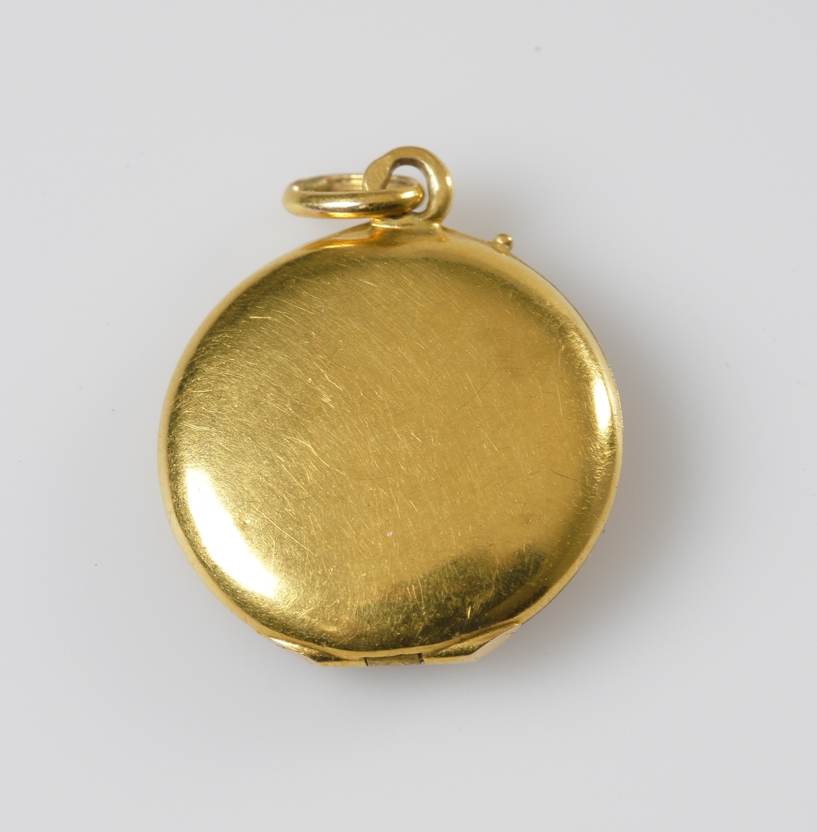 Öppningsbar berlock i 24K guld, med en infäst pärla på locket. Inne i berlocken en pappersguldstjärna.