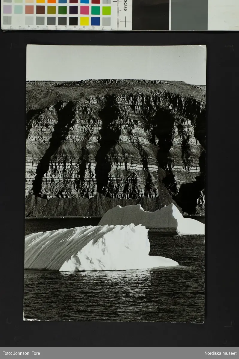Isberg på vattnet framför en bergvägg. Thule, Grönland.