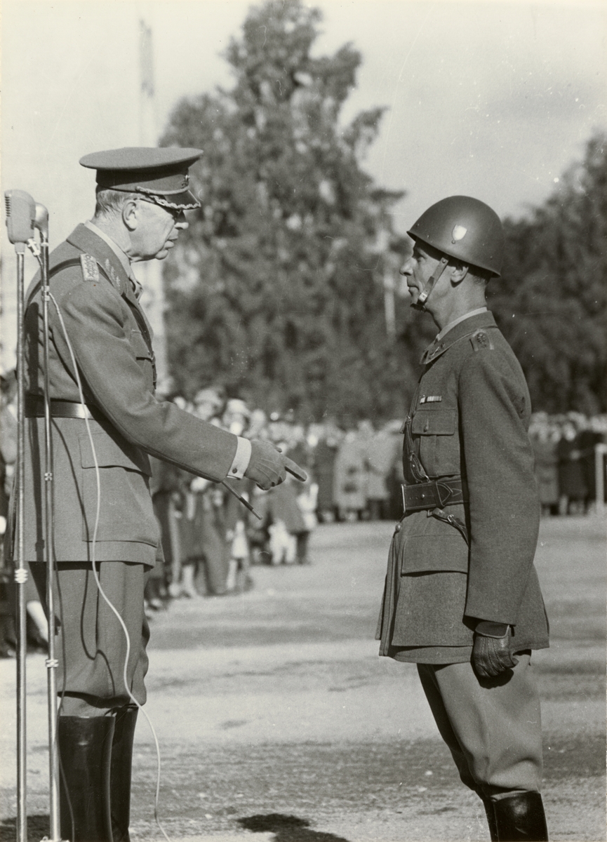 Text i fotoalbum: "Fanöverlämning 27 september 1955. H M Konungen delgiver regementschefen, överste Grewell sitt intryck av inspektion."