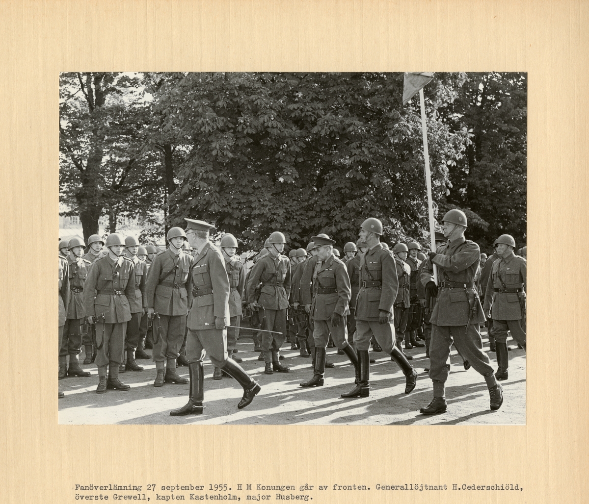 Text i fotoalbum: "Fanöverlämning 27 september 1955. H M Konungen går av fronten. Generallöjtnant H. Cederschiöld, överste Grewell, kapten Kastenholm, major Husberg."