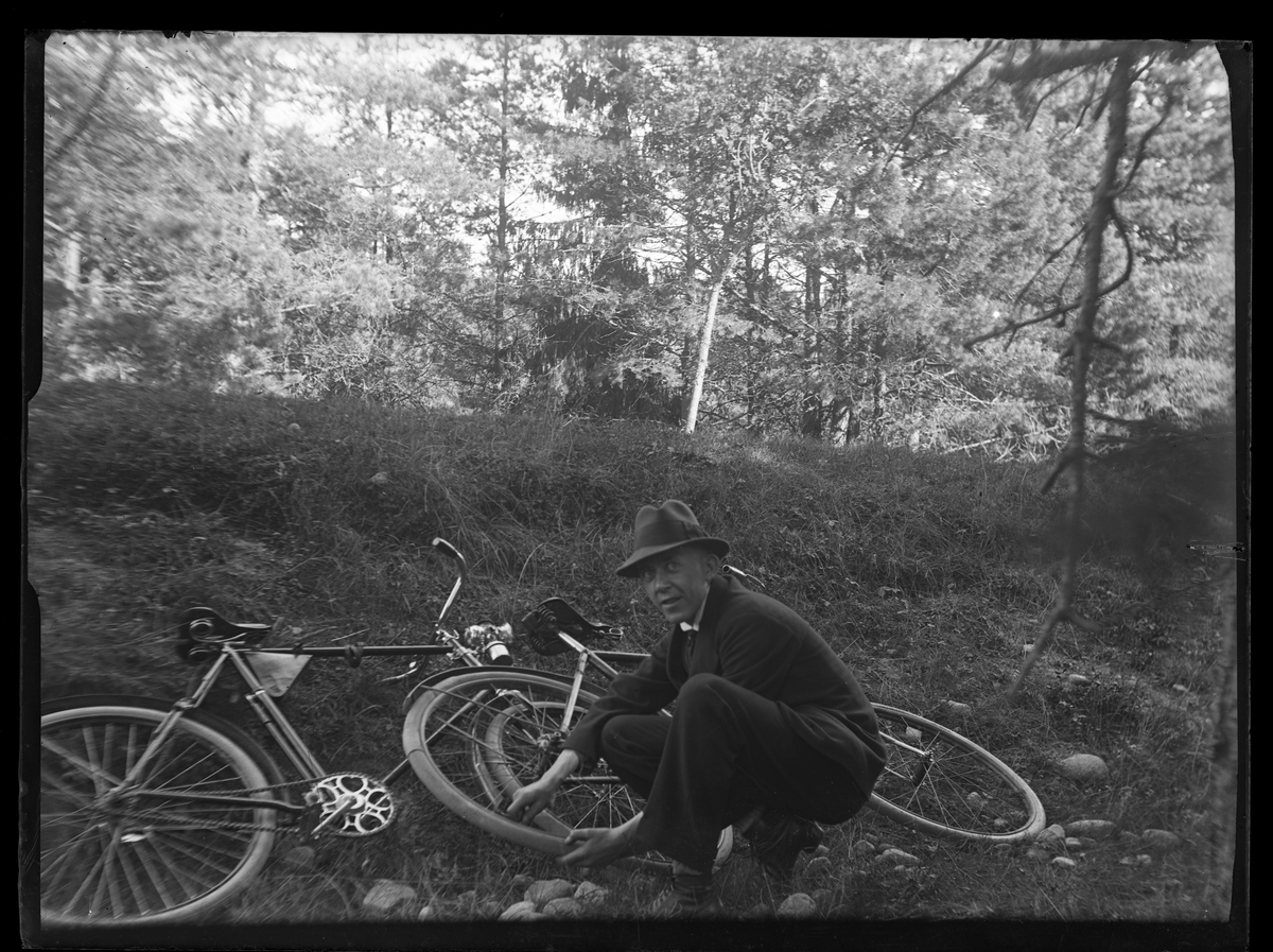 En man med cykel lagar vad som ser ut att vara en punktering.