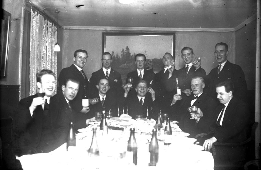 Ett antal män skålar vid festbordet.