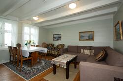 Interiør med sofa, bord med seks stolar, måleri på veggane (Foto/Photo)