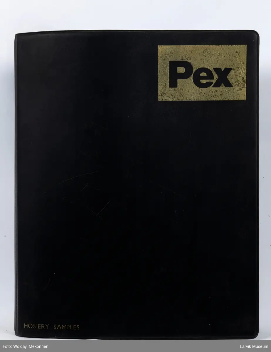 Vareprøver i perm
På forsiden av permen står det: Hosiery samplex  merke:PEX 13 stk. barnesokker pluss noen stoffprøver ligger i en sort plastperm