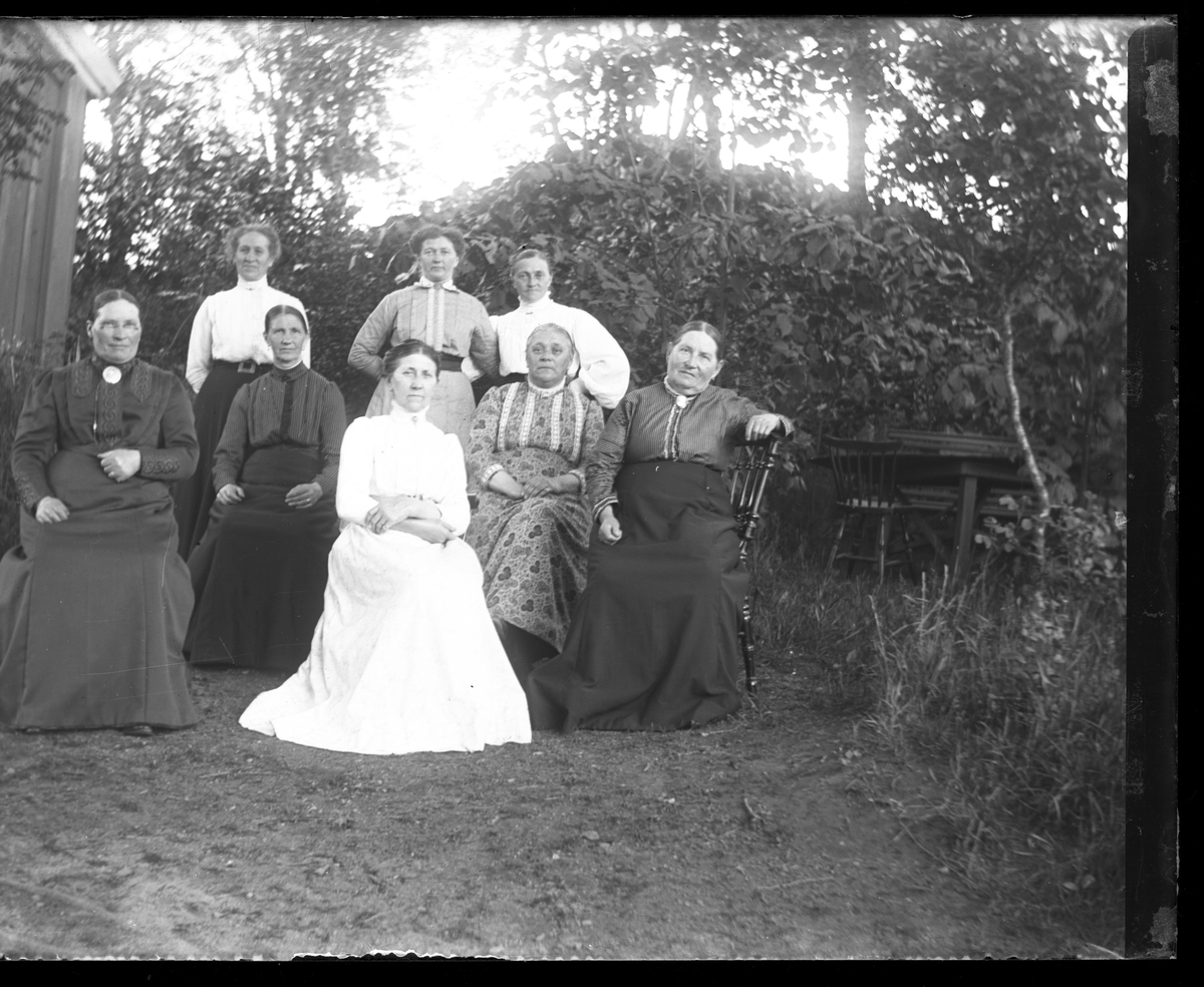 Systrarna Engström tillsammans med en grupp äldre kvinnor i en trädgård. Constance sitter med mönstrad klänning näst längst till höger med Bertha stående bakom och Fredrika sittande framför.
(Bild 1 är beskuren)