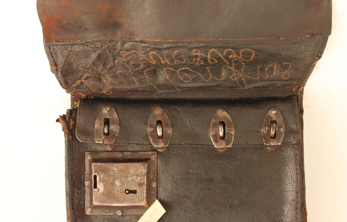 Lösväska av svärtat läder med spännen och låsinrättning. Stor
klaff med sydd inskription: Gyllenfors Qvarsebo.