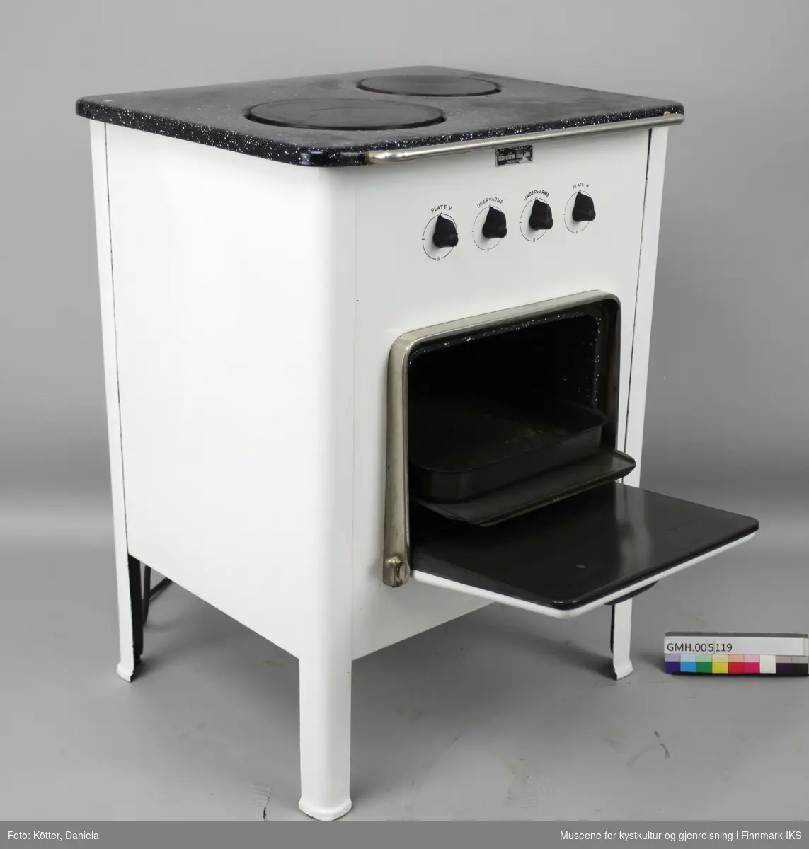 Den elektriske komfyren "Diamant PK 2" har to kokeplater og en stekeovn. Apparatet står på fire ben og har fire vrideknapper, en for hver plate, samt for over- og undervarme i ovnen. På ovnsdøra er det en rund termometer som viser temperaturen i ovnen. I ovnen er det to lave og et dypt stekebrett. Foran på toppen er det en sølvfarget stang.