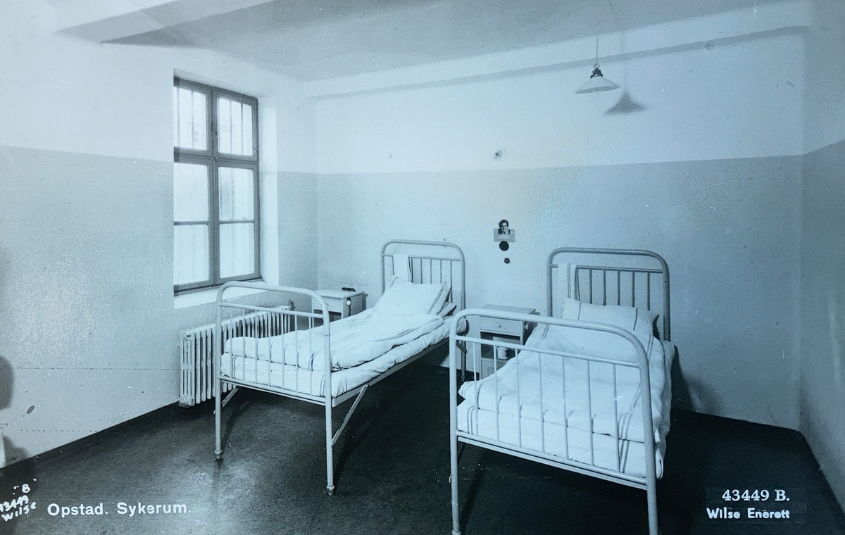 Interiørbilde fra sykestuen ved Opstad tvangsarbeidshus. Rommet er innredet med to sykesenger og to nattbord.