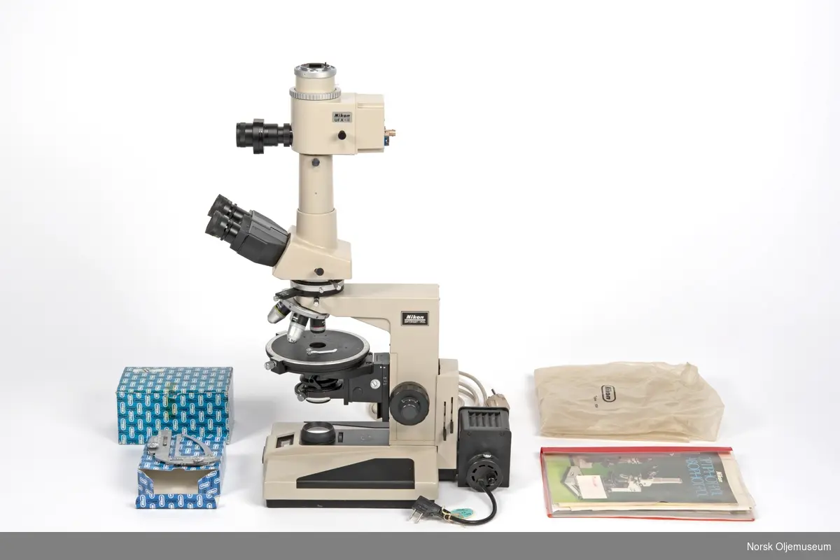 Bærbart polarisasjonsmikroskop med trinoculartubus, fototubus, avtagbar lampe og overtrekk. Tilhørende prøveholder, beholdere til okularer og bruksanvisninger hører og til utstyret.