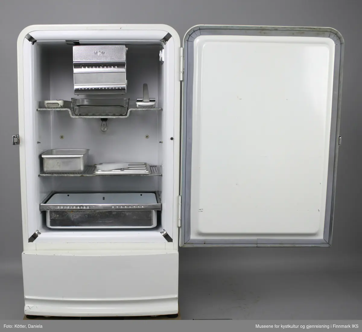 Kjøleskapet er hvit emaljert og har avrundede hjørner. Innvendig finner man et frysefag med dør øverst. Under det er det en gitterbunn med et rektangulær form av glass. Det er i tillegg en til gitterbunn i dette kjøleskapet, samt en uttrekkbar skuffe nederst. Det følger videre med tre isbitformer i aluminium og en i hvit-gjennomsiktig plast, samt en kasse og et brett i aluminium. Brettet har en inndeling i 8 felt. Kjøleskapet har en innvendig belysning med en lyspære i en E27 sokkel.