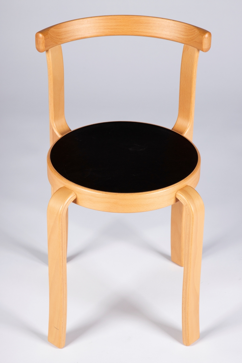 Barnestol i formbøyd og lakkert kryssfiner av bøk med svart sete av linoleum. Stolen har et halvsirkelformet rygglene som er festet til forlengelsen av de to bakre ben. Bena er kilt vinkelrett inn i setets kant og avrundet. Stolsetet er sirkelrundt og stolbena er plassert diagonalt på setet. Stolen kan stables.