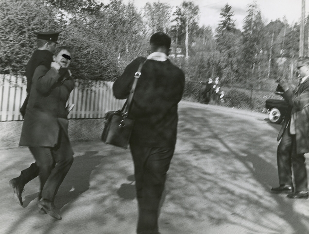 En person blir pågrepet under en demonstrasjon mot sørafrikanske tennisspillere på Madsrud 14. mai 1964. Den arresterte mannen har fått en svart tusj-sladd foran øynene for å skjule hans identitet. En politibetjent har mannen i grep rundt halsen. Arrestanten protesterer. Rundt står et par fotografer og journalister og dokumenterer episoden.  Utstillingstekst¤ Paul A. Røstad (1908-86) vokste opp på Ranheim utenfor Trondheim, og flyttet senere til Oslo der han fikk kontorjobb i et maskinfirma på 1930-tallet. Etter å ha dyrket fotografering som hobby gjennom en årrekke, sa han opp sin stilling og etablerte seg som profesjonell fotograf tidlig på 1950-tallet. Røstad la stor vekt på uavhengighet og drev livet gjennom et enmannsforetak fra sin bopel på Grefsen. Han tok bilder over hele Norge og var særlig opptatt av natur- og kulturlandskaper. Bilder fra gårdsdrift og husdyrholdgår igjen, ved siden av arkitekturfotografering. På 1960-tallet orienterte Røstad seg også mot nyhets- og reportasjefotografering, og leverte bilder blant annet til A-Magasinet. Bildene i utstillingen er alle fra denne fasen og er alle fra Oslo. Ungdomskultur Med Oslo som scene tok Paul A. Røstad mellom 1964 og 1971 en rekke bilder med ungdomskultur som tema.
