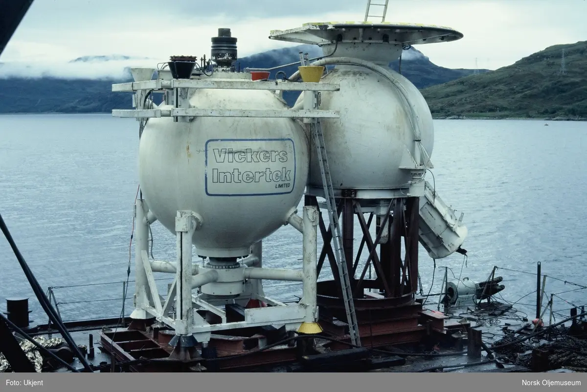 Moduler for et undervannsanlegg heises over kanten fra en båt eller lekter. Det står "Vickers Intertek Limited" på den ene modulen.