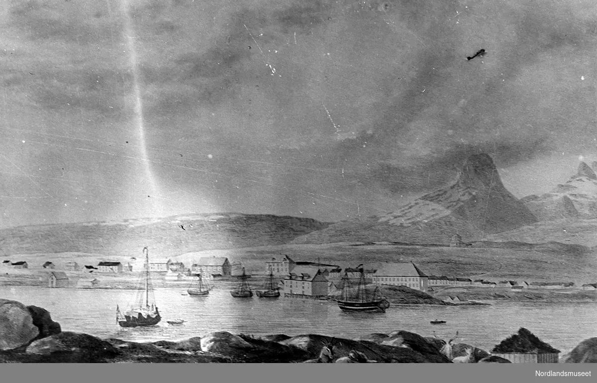 Kopi av maleri av Bodø, eller Hundholmen som det først hette. Maleren står på Nyholmen. Vi ser båter på havnen. Daværende bebyggelse med Jakhellngården dominerer maleriet. I bakgrunnen ser vi Børvasstindene.