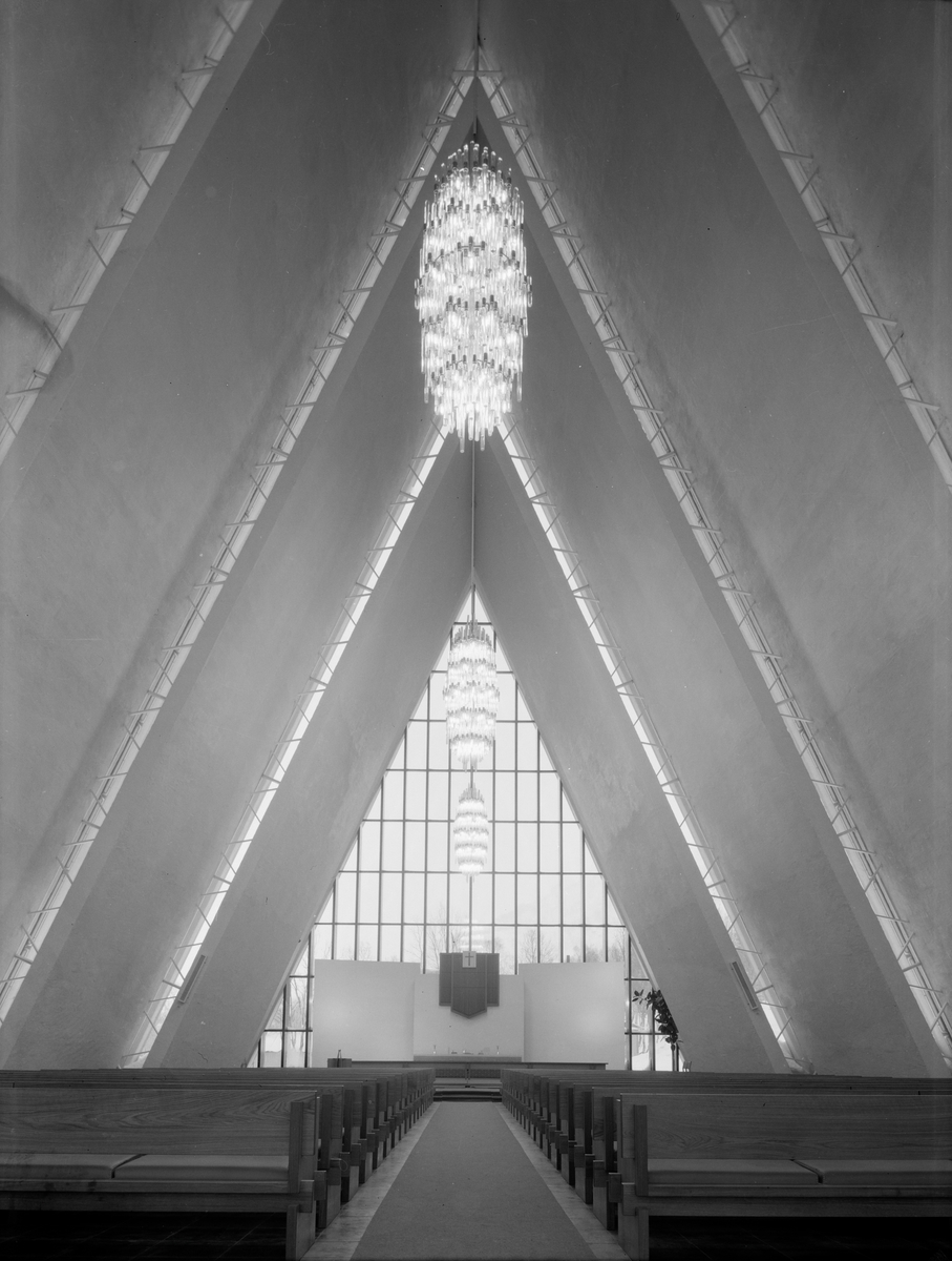 Arkitekturfoto av Tromsdalen kirke, bedre kjent som Ishavskatedralen. Med sitt avtrappede båthusformede eksteriør og sine åpne glassgavler er den blitt et landemerke i området. Kirken blei innviet 19 november 1965.