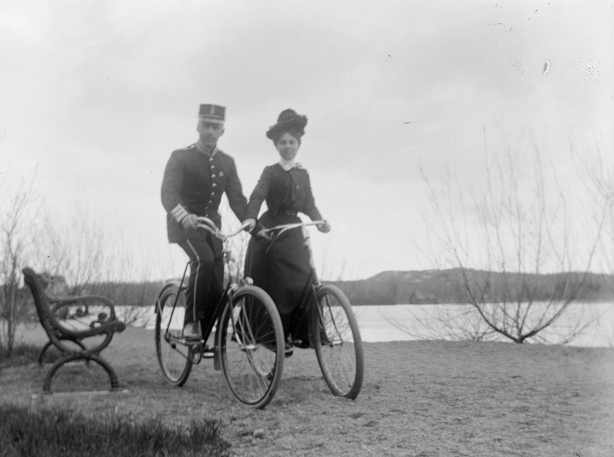 En man och en kvinna på cykel vid en sjö. Mannen är klädd i arméuniform.