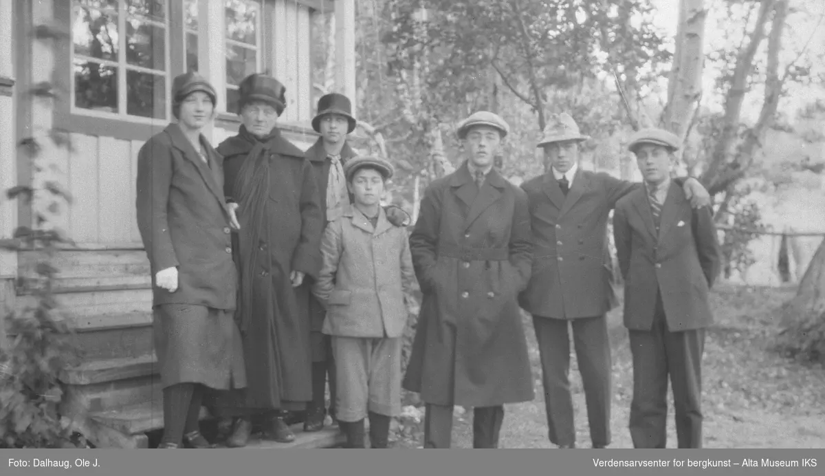 Bilde av 7 menn og kvinner ved hytta til Gunnar Heitmann? 5.aug 1926. 4 menn, 2 kvinner og 1 gutt ved en trapp.