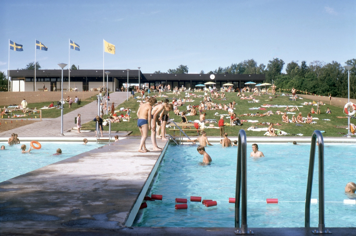Lundbybadet i Mjölby stod klart i tid för stadens 50 årsjubileum 1970. Här en vy över anläggningen en välbesökt sommardag kort efter invigningen.