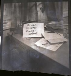 Fotografi av en lapp og noen blader og papirer og en telefon