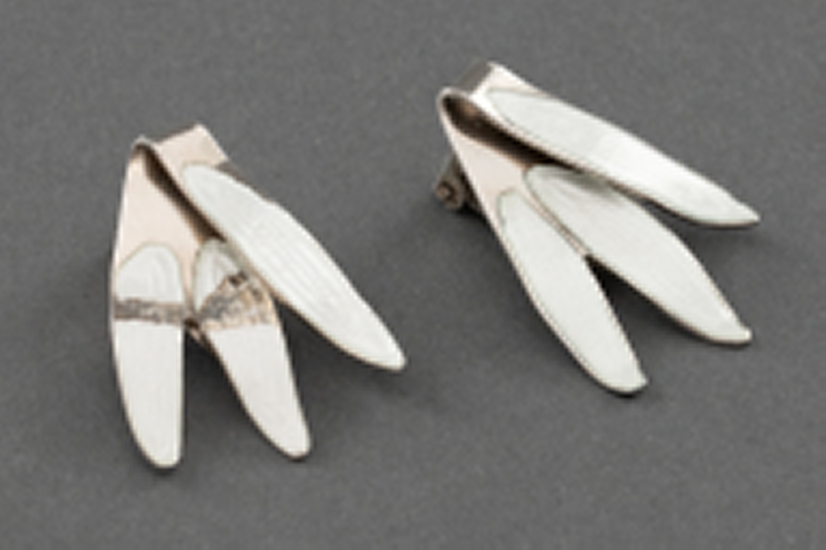 To bladformede øreklips i sølv sterling med hvit speilemalje. Hver øreklips har tre blad. En del skader i speilemaljen på den ene. Se tilstandsrapport.