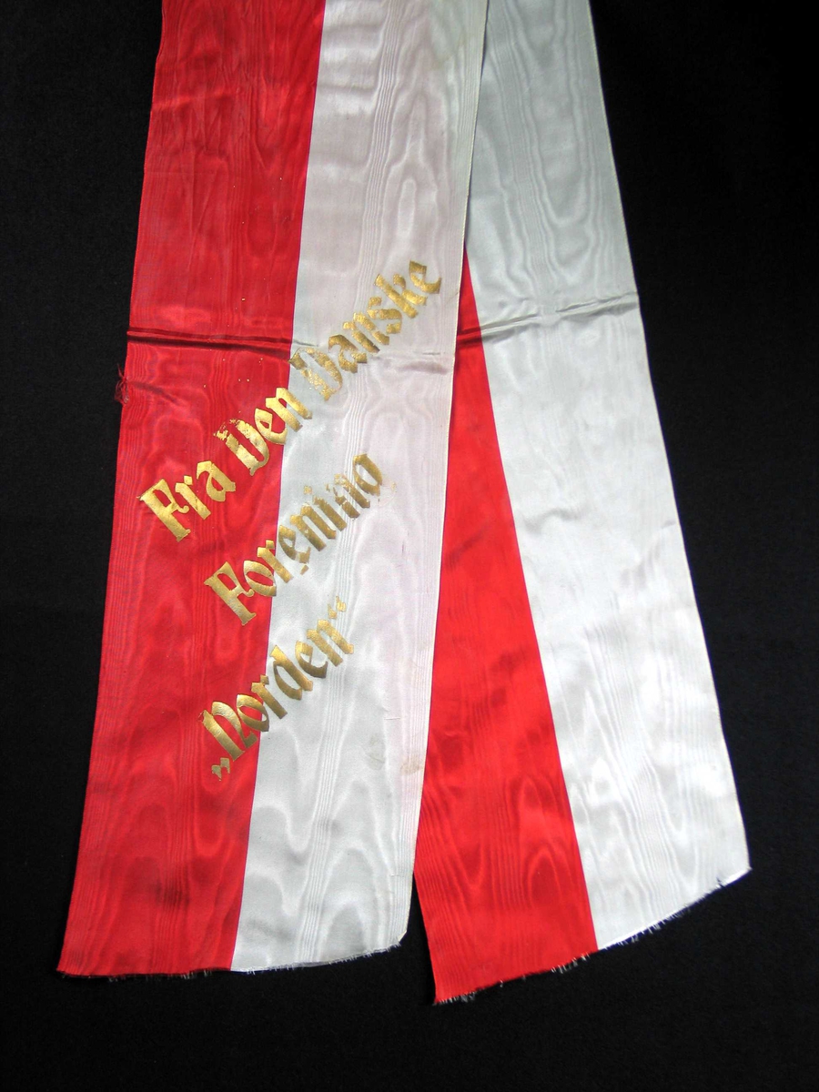 Begravelsessløyfe i rød og hvit silke med tekst i gull.