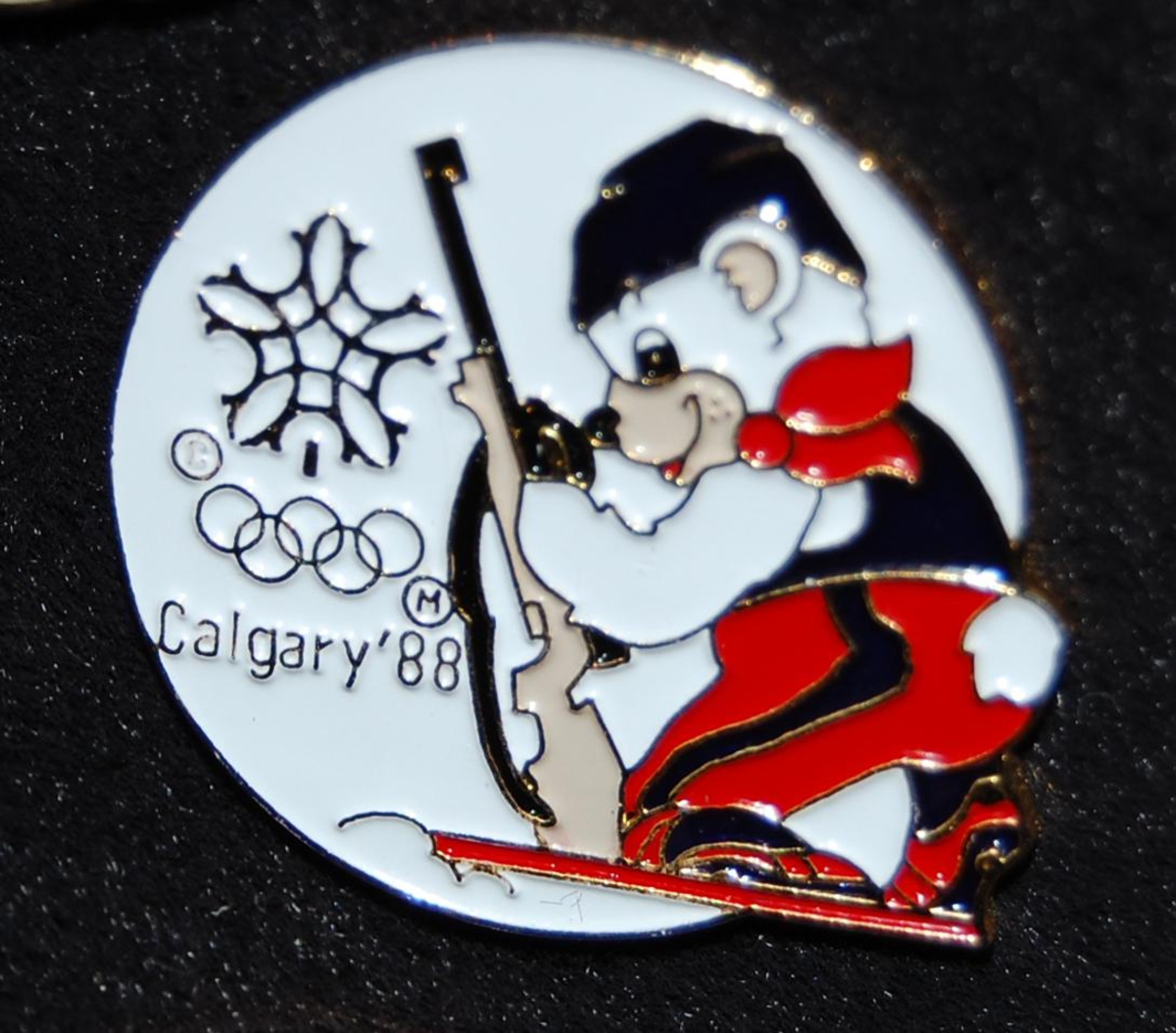 Merke med motiv av en av maskotene for de olympiske vinterleker i Calgary i 1988, Howdy og Hidy, som driver skiskyting.