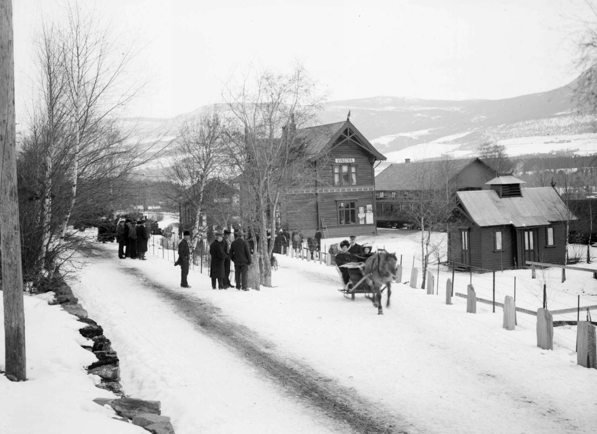 26.03.1909. Hoffrøknene på tur til Fefor. Vinstra jernbanestasjon, folkemengde, hest med slede, vei.