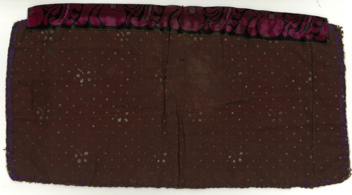Bringeklut. Perlestrikket midtfelt med initialer, geometriske mønstre og årstall 1876. Kantet med eplebånd i overkant, lilla silke langs kantene. Bakstykke av brunrødt, mønstret stoff.