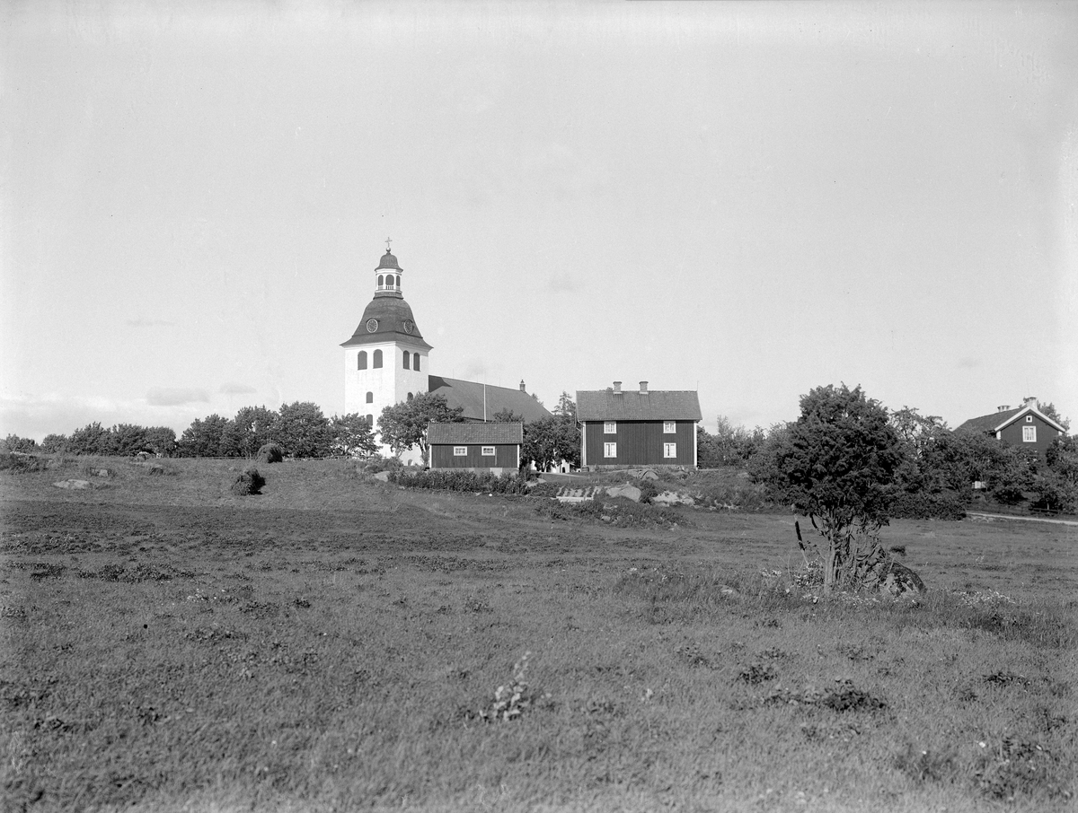 Vy mot Vårdnäs kyrkby 1932. I pastoral idyll på vår sida om kyrkan ligger Komministergården.