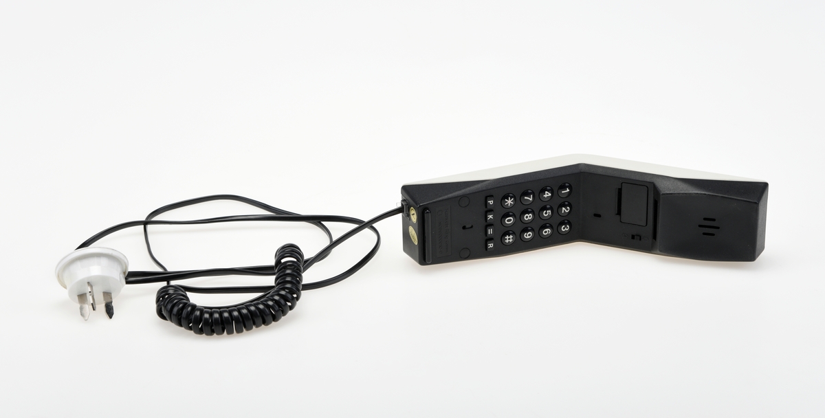 Hvit Ouno telefon fra Scanvest Ring Communications. Strømkabelen er av flat plast med hurtigkopling. Mangler tilhørende vegg/bordfeste.